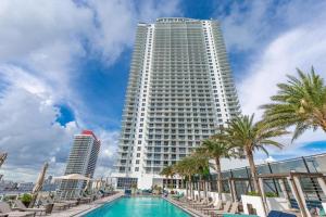 a large white building with a pool and palm trees at Ocean Breeze Retreat - Pool Gym Access Views in Hallandale Beach