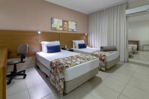 a hotel room with two beds and a desk at Comfort Hotel Bauru in Bauru