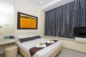a hotel room with a bed and a television at Hotel 81 Elegance in Singapore +4 photos