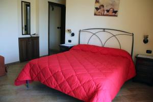 a red bed with a red comforter in a bedroom at Le Villette in Frascineto