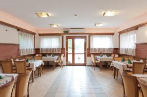 a restaurant with tables and chairs and windows at Hotel Kardosfa in Zselickisfalud