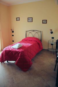 a bed with a red comforter in a room at Le Villette in Frascineto