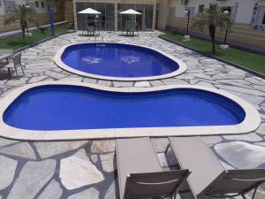 uma piscina com água azul num pátio com cadeiras em Village Hotel em Cáceres