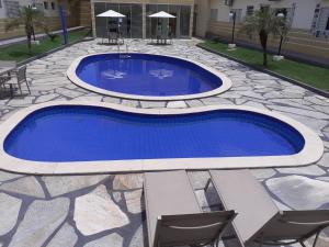a pool with blue water in a patio with chairs at Village Hotel in Cáceres