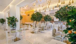 um restaurante com mesas brancas, cadeiras e árvores em Epirus Palace Congress & Spa em Ioannina