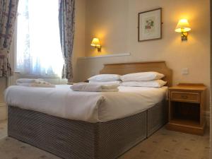 a bedroom with a large bed with white sheets and pillows at Ullswater Hotel in Bournemouth