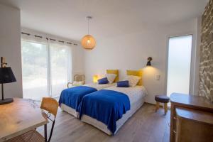 a bedroom with a bed with blue and yellow pillows at Les Jardins du Cloestro in Kervignac