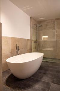 eine große weiße Badewanne im Bad mit Dusche in der Unterkunft LUVA Resorts Kappl - Chalet K in Kappl