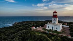 a lighthouse on a hill next to the ocean at Golden Tulip Porto-Vecchio in Porto-Vecchio