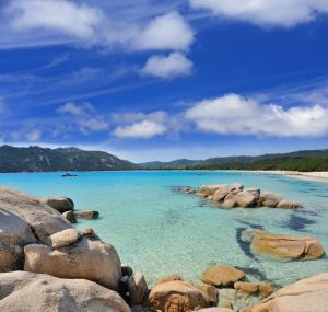 a view of a beach with rocks in the water at Golden Tulip Porto-Vecchio in Porto-Vecchio