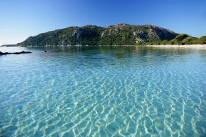 a large body of water with a mountain in the background at Golden Tulip Porto-Vecchio in Porto-Vecchio