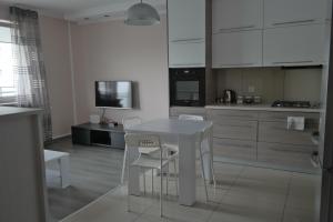 a white kitchen with a white table and chairs at Apartament Ryska 3A in Białystok