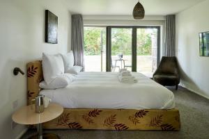 um quarto com uma cama grande e uma cadeira em Tuddenham Mill Luxury Hotel em Tuddenham