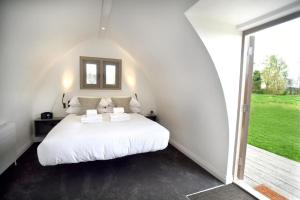 a bedroom with a white bed and a large window at Tuddenham Mill Luxury Hotel in Tuddenham