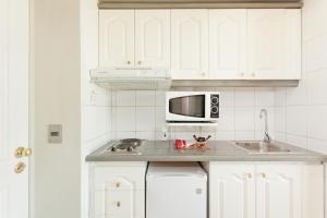 cocina blanca con fregadero y microondas en Apart Hotel Cambiaso, en Santiago