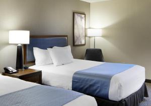 a hotel room with two beds and a chair at Wingate by Wyndham St. Clairsville/Wheeling in Saint Clairsville +15 photos