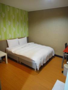 um quarto com uma cama branca num quarto em Baoshan Hotel em Zhongli