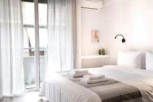 a white bedroom with a bed with towels on it at Homz Studios Neapolis in Athens