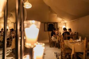 a group of people sitting at tables in a restaurant at Aiour Luxury Camp in Merzouga