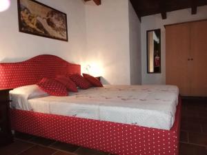 een rood bed met witte lakens en rode kussens bij Villetta Bouganvillea in SantʼAnna Arresi