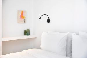 a bedroom with white walls and a bed with white pillows at Homz Studios Neapolis in Athens