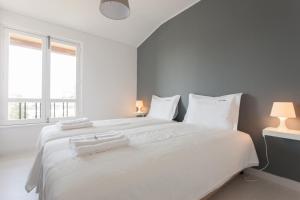 a white bedroom with a large white bed with white pillows at FLH - Ericeira Beach Apartments in Ericeira