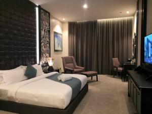 a hotel room with a bed and a flat screen tv at Vangohh Eminent Hotel & Spa in Bukit Mertajam