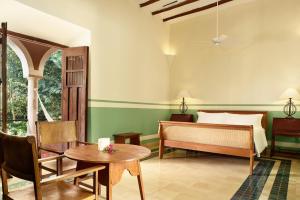 a bedroom with a bed and a table and chairs at Hacienda San Jose in Tixkokob