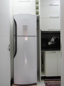 a white refrigerator in a kitchen with white cabinets at Apartamento Coral - 1 quadra do Mar in Balneário Camboriú