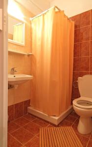 ein Badezimmer mit einem orangefarbenen Duschvorhang und einem WC in der Unterkunft Sibylla Hotel in Delphi