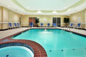 a pool in a hotel room with chairs and tables at Holiday Inn Express - Eunice, an IHG Hotel in Eunice