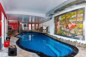 a swimming pool in a house with a large painting on the wall at Sporthotel Snowwhite in Obertauern