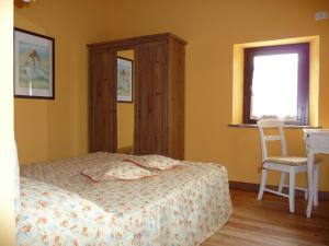 1 dormitorio con 1 cama, 1 silla y 1 ventana en Agriturismo Casale il Gallo Bianco en Offagna