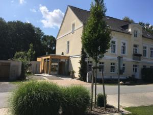 a white house with a tree in front of it at Schönhagener Mühle in Pritzwalk