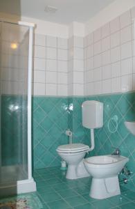 y baño de azulejos verdes con aseo y ducha. en Agriturismo Casale il Gallo Bianco, en Offagna