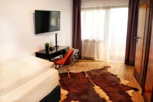 Sala de estar con cama, escritorio y TV en Hotel Sonnenschein, en Freudenstadt