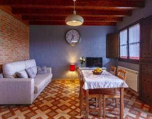 a living room with a table and a couch and a clock at Apartamentos Miradorderodiles Miramar in Villaviciosa