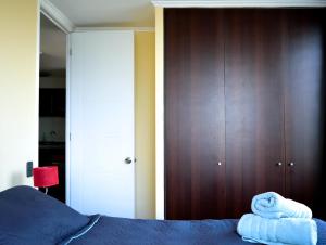 1 dormitorio con 1 cama azul y armarios de madera en Santiago Furnished Apartments, en Santiago