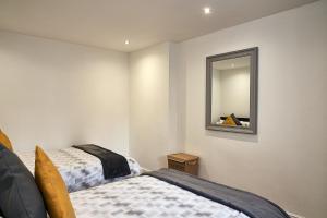 een slaapkamer met 2 bedden en een spiegel bij Deluxe Town Center Apartment in High Wycombe