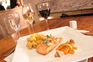 a plate with a piece of fish with vegetables and wine glasses at Hotel Montecarlo Viña del Mar in Viña del Mar +67 photos