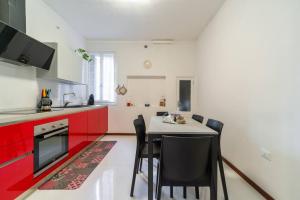 uma cozinha com armários vermelhos e uma mesa com cadeiras em San Marco 4893 em Veneza