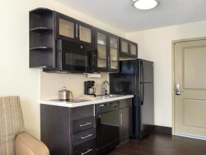 a kitchen with black cabinets and a black refrigerator at Candlewood Suites Enid, an IHG Hotel in Enid