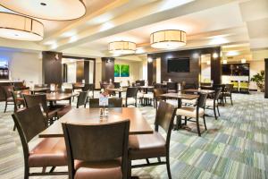 a restaurant with tables and chairs and a flat screen tv at Holiday Inn Express - Sault Ste. Marie, an IHG Hotel in Sault Ste. Marie