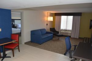 ein Wohnzimmer mit einem blauen Stuhl und ein Zimmer mit einem Bett in der Unterkunft Holiday Inn Express & Suites Waterville - North, an IHG Hotel in Waterville