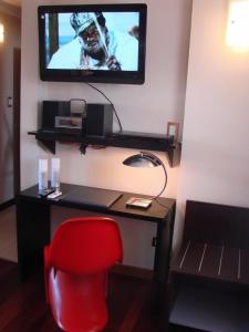 Zoom Apartments Hotel Boutique في قرطبة: غرفة بها مكتب مع كرسي احمر وتلفزيون