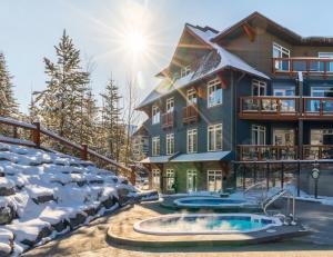 une maison dans la neige avec un bain à remous dans l'établissement Blackstone Mountain Lodge by CLIQUE, à Canmore