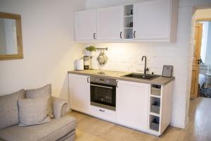 a kitchen with white cabinets and a sink and a couch at Downtown Apartment Rentals in Šiauliai