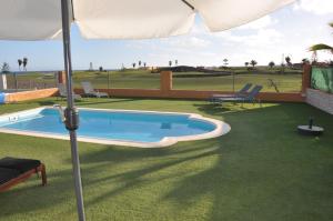 a swimming pool with an umbrella in a yard at Villa Surprise only Solar Energy in Caleta De Fuste