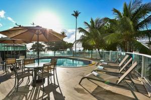 a patio area with a pool, chairs and umbrellas at Radisson Recife in Recife