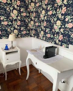 um quarto com uma secretária branca e um papel de parede floral em B&b Querini em Roma